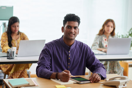 Portrait of smiling Indian businessman signing document on tablet computerの写真素材