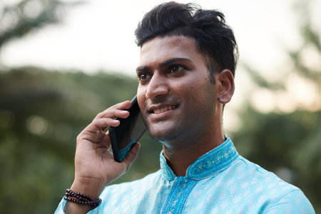 Smiling Indian man talking on phone with friend of family memberの写真素材