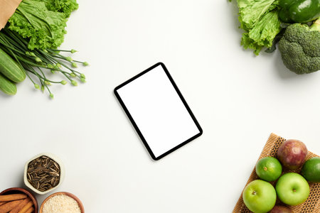 Digital tablet with white screen on table with fresh fruits and vegetablesの写真素材
