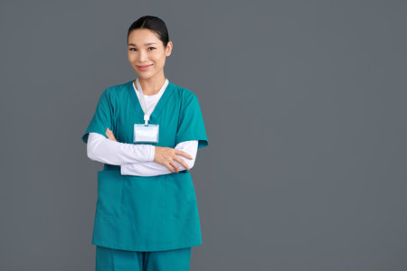 Studio portrait of rehabilitation nurse in green uniform standing with arms crossedの写真素材