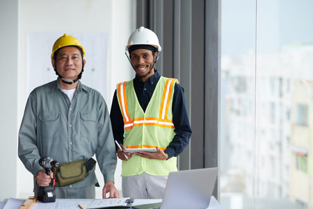 Portrait of smiling foreman and builder with drill smiling at camera