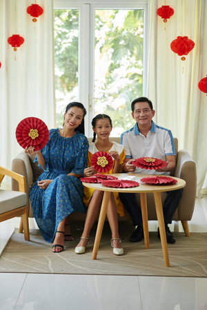 Cheerful family of three showing paper decorations they prepared for Spring festivalの写真素材