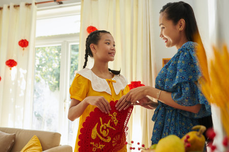 Smiling mother explaining teenage girl how to decorate house for Tetの写真素材