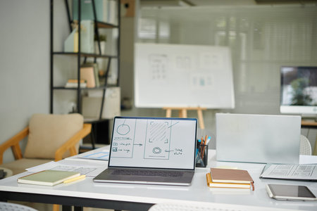 Laptop with mobile interface wireframe on screen, workplace of ui designer