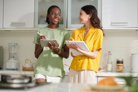College girls standing in dorm kitchen and discussing homeworkの写真素材