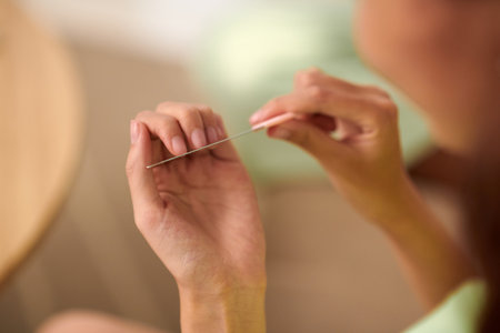 Hands of teenage girl filing nails with metal fileの写真素材
