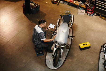 Mechanic using application on tablet computer when detecting problems in motorcycle, top view