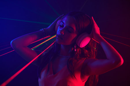 Woman in headphones dancing in neon lights in night clubの写真素材