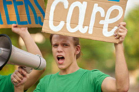 Portrait of eco-volunteer showing placard and shouting in loudspeakerの写真素材