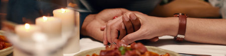 Header of hands of young intercultural valentines sitting by served table with homemade food and...