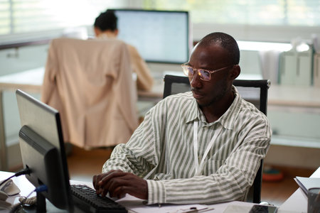 Pensive businessman in glasses filling document at his office deskの写真素材