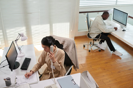 Office manager filling document with clients data when working at her deskの写真素材