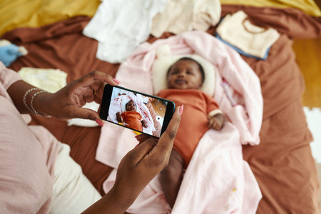Hands of mother photographing baby girl on smartphone