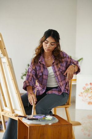 Calm girl painting picture on canvas in her studio