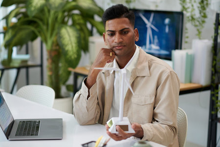 Serious contemplating engineer looking at improved model of wind turbine