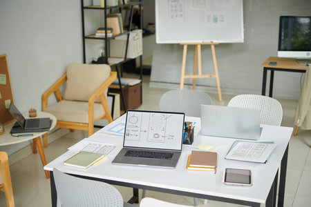 Desk with laptops and planner in office of small IT company