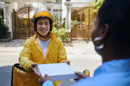Smiling Vietnamese delivery man giving woman pizza box