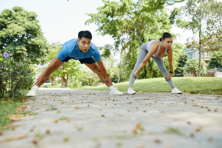 Fit young couple warming up and stretching legs before running in park