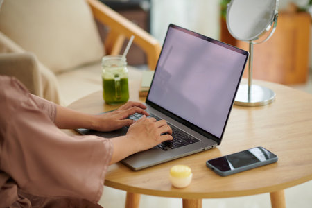 Cropped image of woman in satin robe working on laptopの写真素材