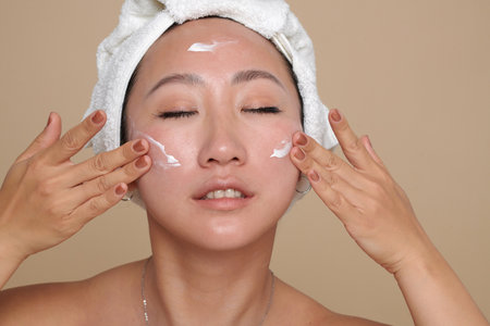 Face of young woman applying skincare product after deep cleansingの写真素材