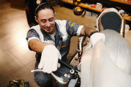 Smiling repairman checking leverage of motorcycleの写真素材