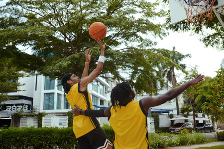 Man throwing ball in basket when his friend playing defense in streetballの写真素材