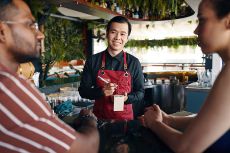 Smiling waiter taking food order in restaurant