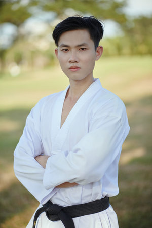 Portrait of serious confident taekwondo athlete wearing dobok with black belt