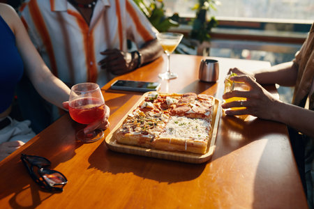 Closeup image of friends eating pizza and having drinks when hanging out in cafeの写真素材