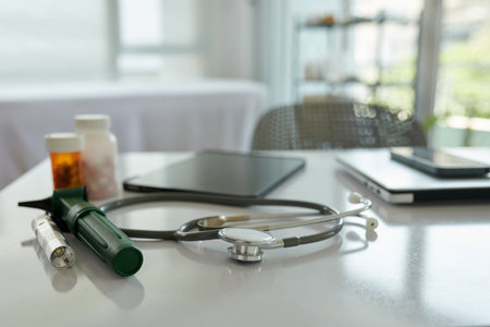 Stethoscope, otoscope, medicine and laptop on desk of general practitionerの写真素材