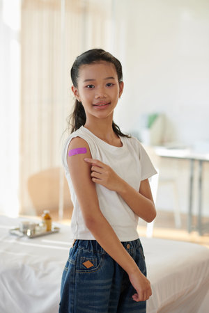 Smiling teenage girl showing pink bandage on her shoulderの写真素材