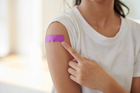 Cropped image of girl pointing at glittery bandage on her arm