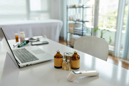 Vials with medicine and contactless thermometer on desk of physicianの写真素材