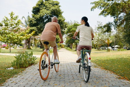 Active man and woman riding bicycles in city parkの写真素材