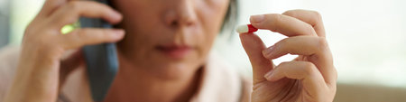 Web banner with sick mature woman calling doctor before taking pillの写真素材