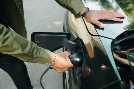 Closeup image of electric car owner putting plug in charge portの写真素材