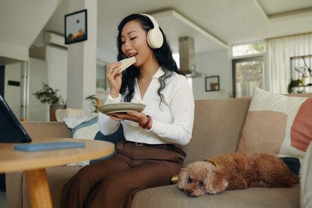 Young woman eating sandwich when watching webinar on laptop at home