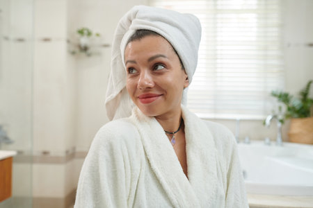 Portrait of smiling woman in bath robe and towel on her hairの写真素材
