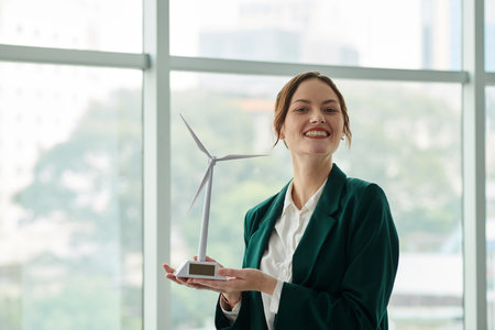 Happy businesswoman holding small model of wind turbineの写真素材