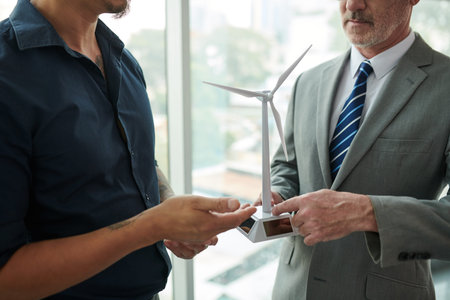 Cropped image of business people discussing wind turbine model in meeting