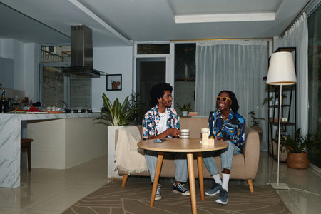 Young Black couple spending evening at home, having tea and chatting