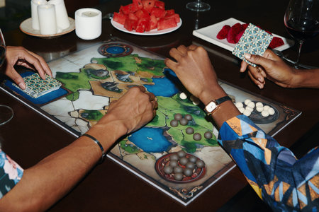 Hands of best friends playing board game at home