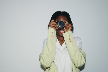 Smiling Black young woman taking photos on digital cameraの写真素材