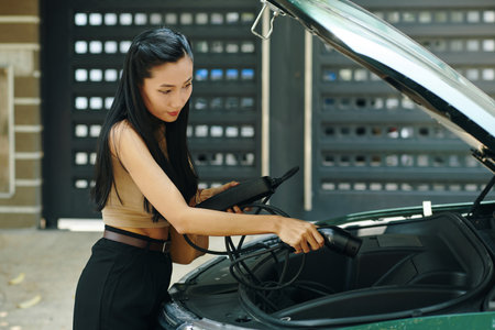 EV owner taking charging cable out of trunkの写真素材