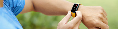 A close-up shot of a smartwatch displaying heart rate monitor during an outdoor exercise sessionの写真素材