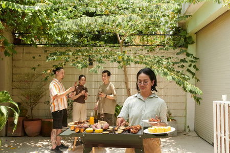 Woman taking roasted prawns from grill to eat at partyの写真素材
