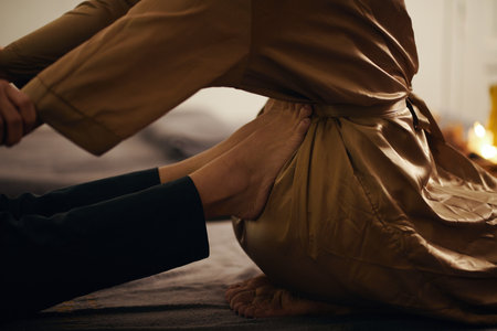Closeup image of masseuse pushing lower back of client with her feetの写真素材