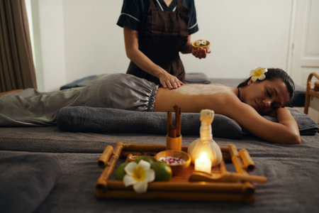 Beautician applying salt peeling on back of womanの写真素材