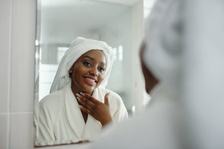 Smiling Woman in Bathrobe Looking at Mirrorの写真素材