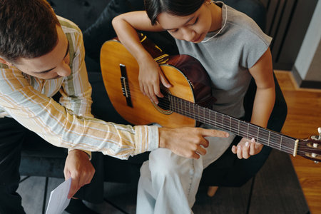 Teaching Guitar Chords to Female Music Learner on Couchの写真素材